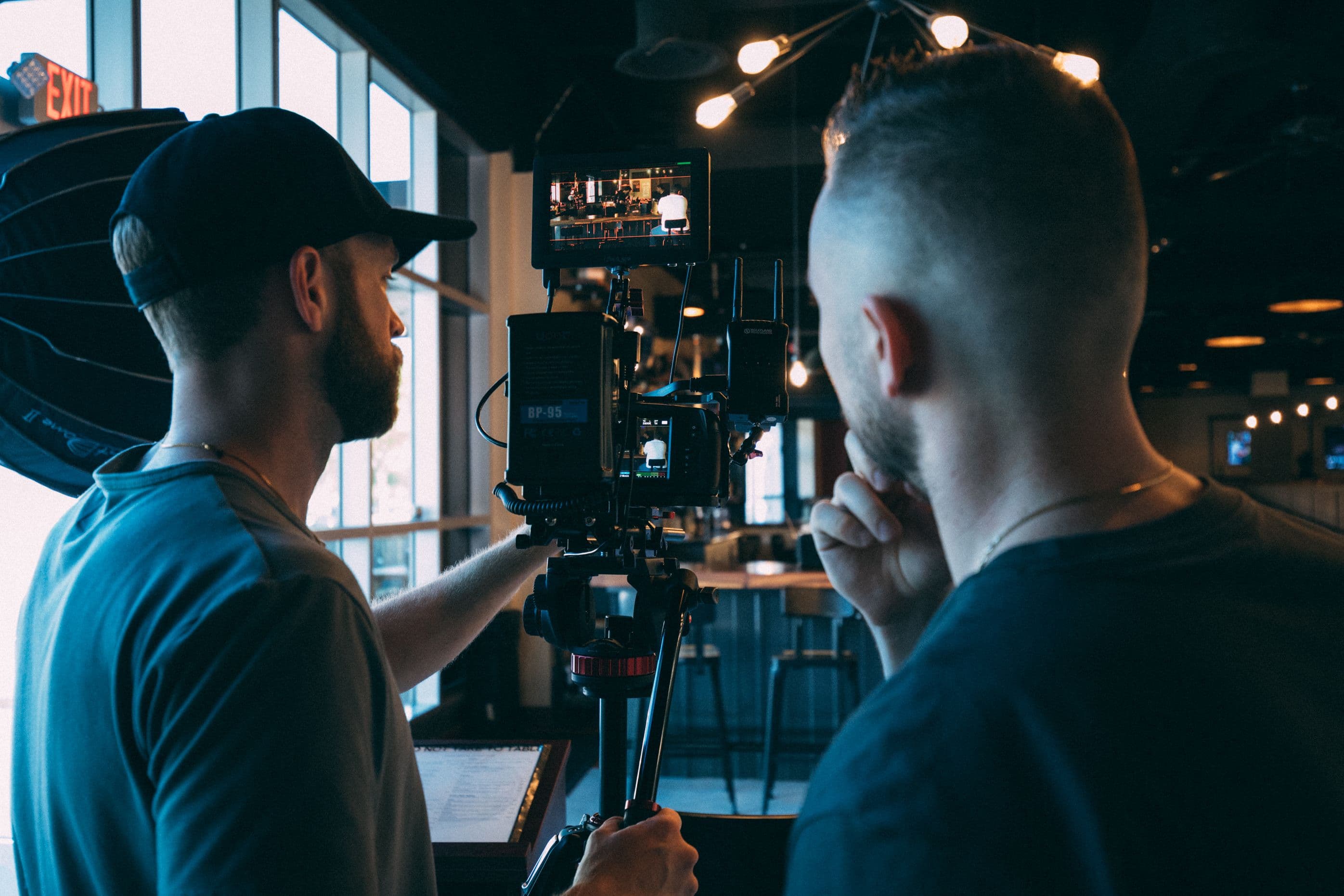 A camera operator filming a conversation in a cafe